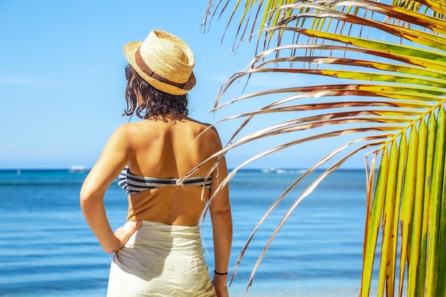 Een jonge vrouw met een hoed op het strand van West End op het eiland Roatan, Honduras