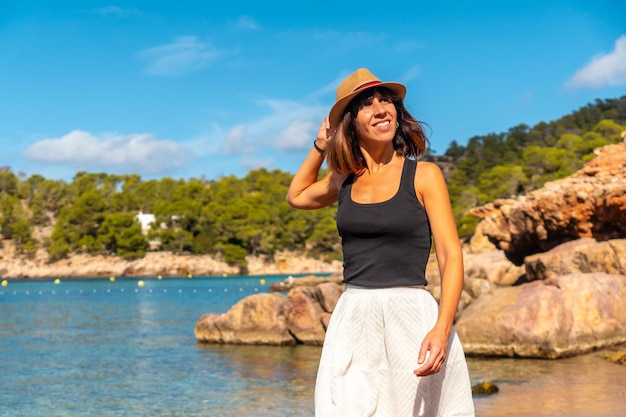 Een jonge vrouw met een hoed op vakantie op Ibiza op het strand van Salada y Saladeta Balearic