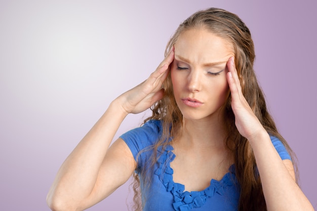 Een jonge vrouw met een hoofdpijn die het hoofd vasthoudt