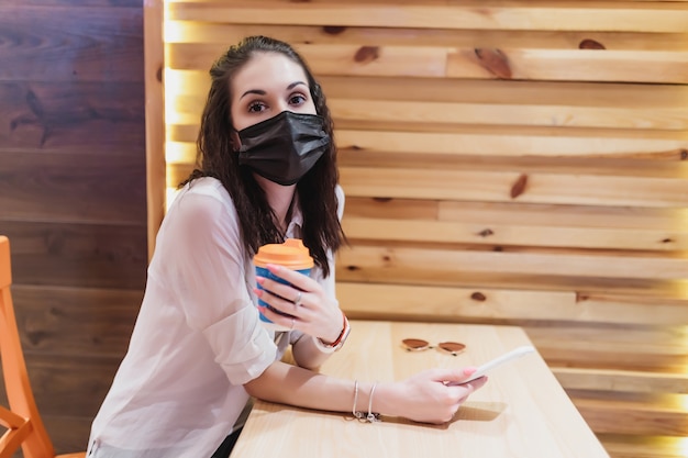 Een jonge vrouw met een masker tegen het virus ging koffie drinken. De stad is in quarantaine. Van hoge kwaliteit