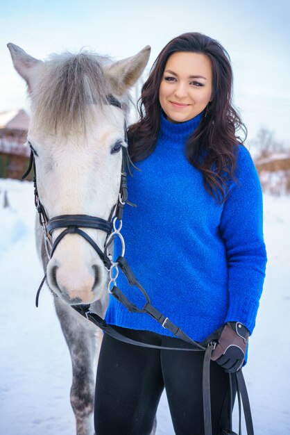 Een jonge vrouw met een mooi winter wit paard