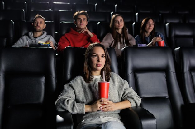 Een jonge vrouw met een rode beker in haar handen kijkt aandachtig naar een film Een vrouw kwam naar de première in de bioscoop