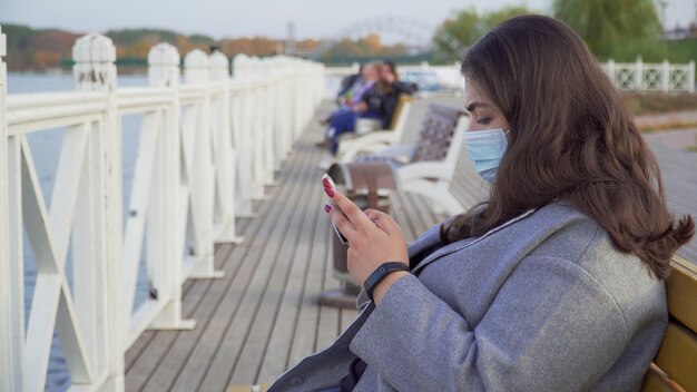 Foto een jonge vrouw met een telefoon in haar handen die een masker draagt