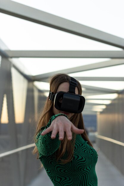 Foto een jonge vrouw met een virtual reality-bril die haar hand uitstrekt naar de camera op een voetgangersbrug