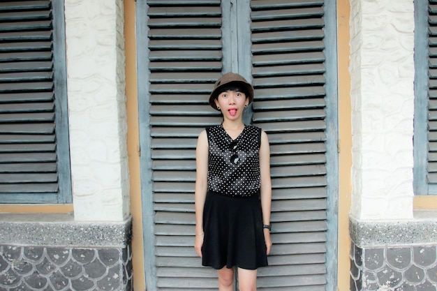 een jonge vrouw met een zwarte jurk en een zwarte hoed staat voor de deur