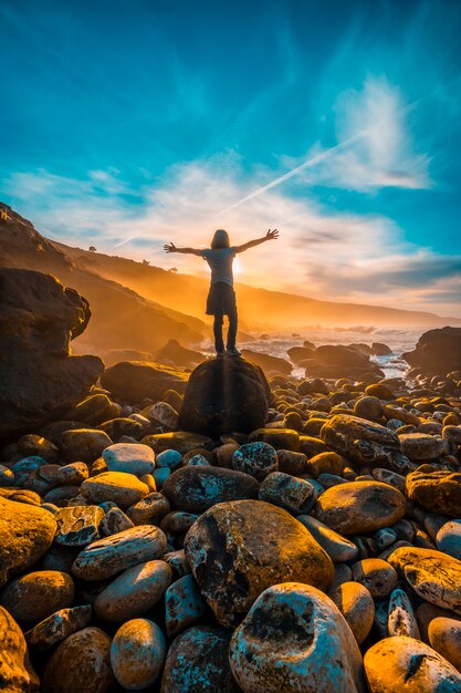 Een jonge vrouw met haar rug naar de zonsondergang aan de kust van Jaizkibel bij San Sebastian. Baskenland