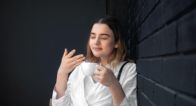 Een jonge vrouw met koffiekopje in zwart café-interieur