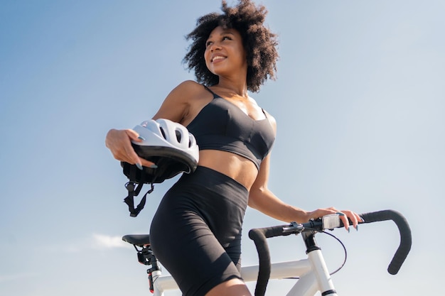 Een jonge vrouw met krullend haar die tevreden is met de activiteit van fietsen in een trainingspak