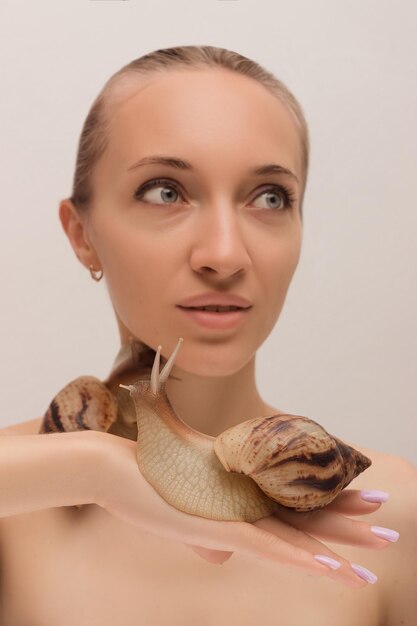 Foto een jonge vrouw met slakken op haar gezicht cosmetologie en verjonging clear skin