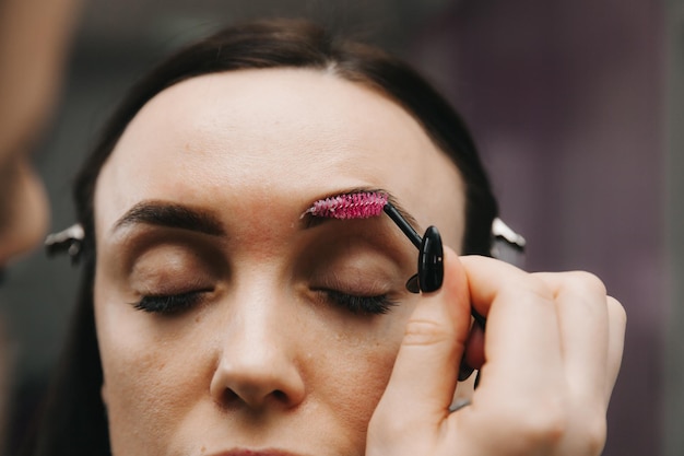 Een jonge vrouw ondergaat een wenkbrauwcorrectieprocedure in een schoonheidssalon close-up het meisje schildert haar wenkbrauwen in de salon