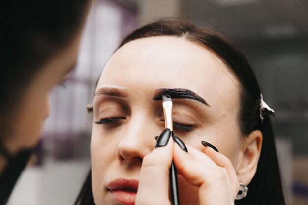 Een jonge vrouw ondergaat een wenkbrauwcorrectieprocedure in een schoonheidssalon close-up het meisje schildert haar wenkbrauwen in de salon