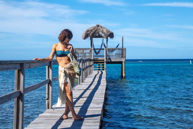 Een jonge vrouw op een houten loopbrug boven de Caribische Zee op Roatan Island. Honduras