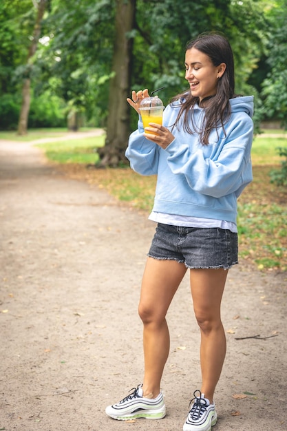 Een jonge vrouw op een wandeling in het park met sinaasappelsap