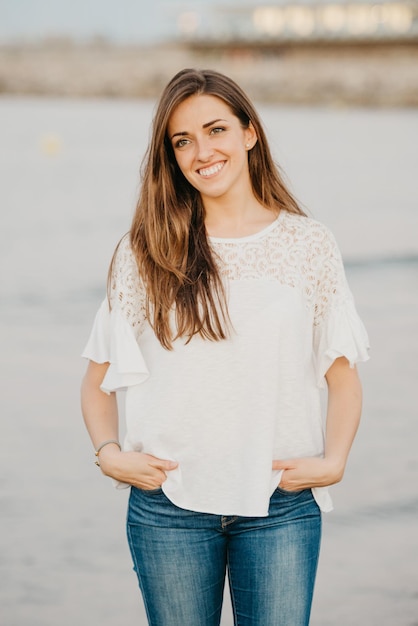 Een jonge vrouw poseert op een zandstrand in de buurt van water in de schemering in Spanje