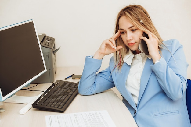 Een jonge vrouw praat met een klant aan de telefoon op kantoor Een vrouw in een pak werkt in een kantoor