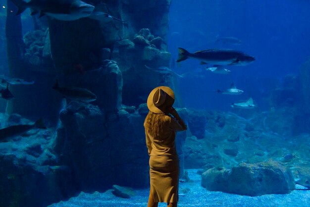 Foto een jonge vrouw raakt een stingray-vis aan in een tunnel van een oceanarium