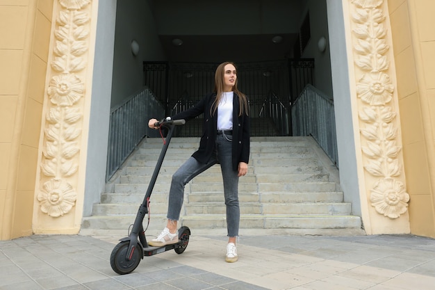 Een jonge vrouw rijdt op een elektrische scooter in de stad. Milieuvriendelijk vervoer