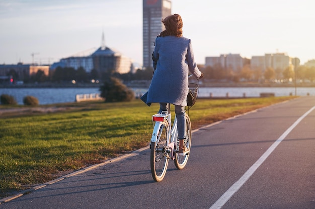 Een jonge vrouw rijdt op een zonnige herfstochtend met een retro vintage fiets naar de stad.