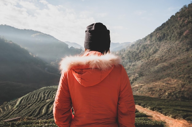 Een jonge vrouw staat alleen op de top van de berg, hij staat en kijkt naar de zonsopgang boven de top van de berg en de theeplantage. Ze voelde zich gelukkig om in het weekend te reizen