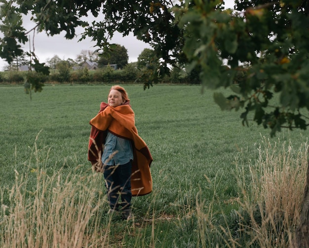 Een jonge vrouw staat in een veld met een rode deken waarop 'het woord' erop staat