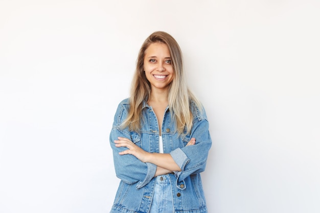 Een jonge vrouw staat met haar armen over elkaar op haar buik geïsoleerd op een witte achtergrond