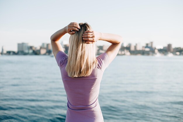 Foto een jonge vrouw staat met haar rug op een zonnige dag op de pier.