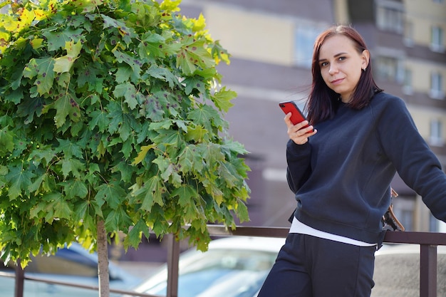 Een jonge vrouw staat op straat met haar mobiele telefoon in haar hand Een vrouw die een smartphone gebruikt, gebruikt internet op de binnenplaats van een woongebouw