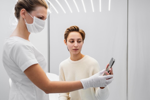 Foto een jonge vrouw toont voorbeelden van de baan die ze wil krijgen op haar smartphone schoonheidssalon van hoge kwaliteit