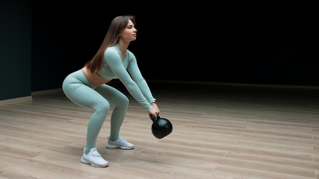 Een jonge vrouw traint thuis met een kettlebell