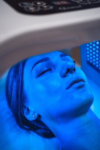 Een jonge vrouw verzorgt haar huid met een led-masker in een schoonheidssalon