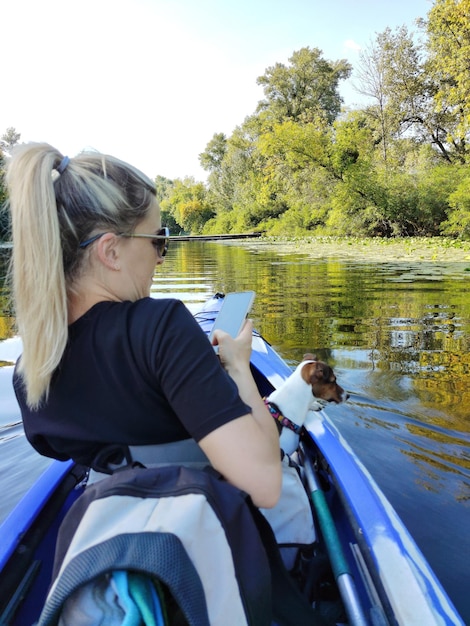 Foto een jonge vrouw zeilt op een boot met haar jack russell terrier hond en neemt een foto van haar