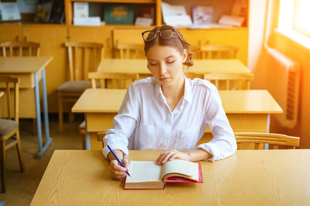 Een jonge vrouw zit aan een bureau in een wit overhemd