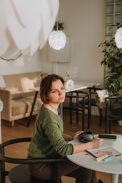 Een jonge vrouw zit aan een tafel in een café