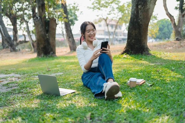 Een jonge vrouw zit op het gras met een laptop.