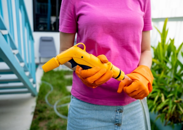 Foto een jonge vrouw zorgt voor de tuin, water geeft, bemest en snoeit planten.