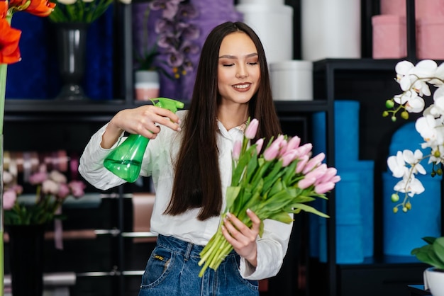 Een jonge vrouwelijke bloemist zorgt voor bloemen in een gezellige bloemenwinkel en verzamelt boeketten Bloemisten en het maken van emmers in een bloemenwinkel Klein bedrijf
