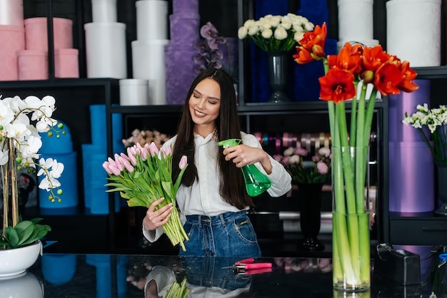 Een jonge vrouwelijke bloemist zorgt voor bloemen in een gezellige bloemenwinkel en verzamelt boeketten Bloemisten en het maken van emmers in een bloemenwinkel Klein bedrijf