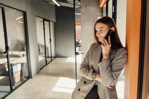 Een jonge vrouwelijke marketeer in het kantoor gebruikt de telefoon om te communiceren met een klant een werknemer