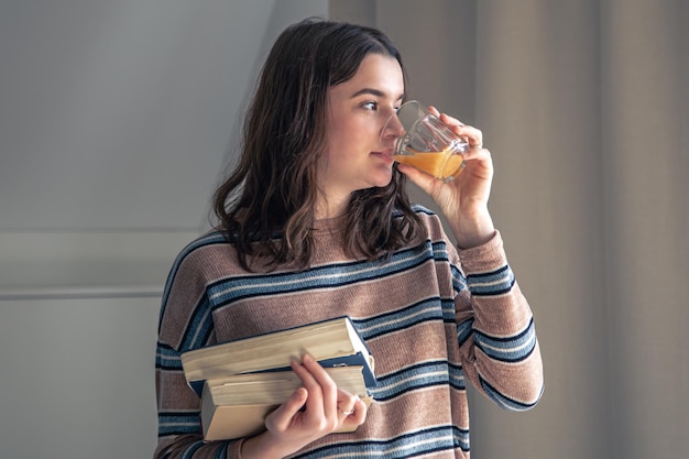 Een jonge vrouwelijke student met boeken in haar handen in de kamer