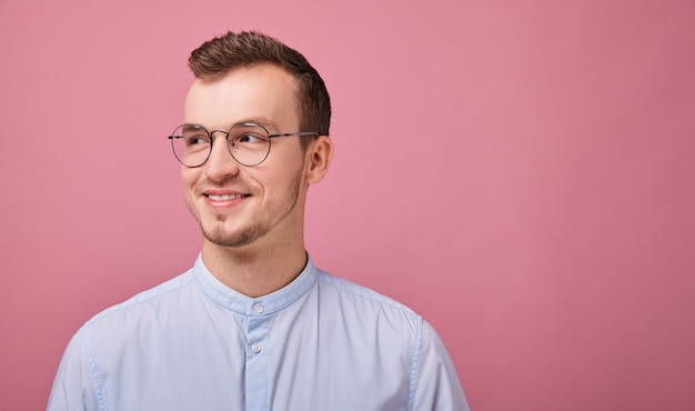 Een jonge werknemer in een hemelsblauw shirt staat op roze