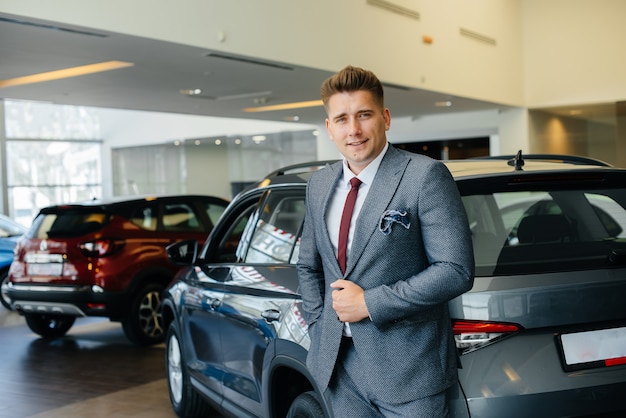 Een jonge zakenman kijkt naar een nieuwe auto in een autodealer