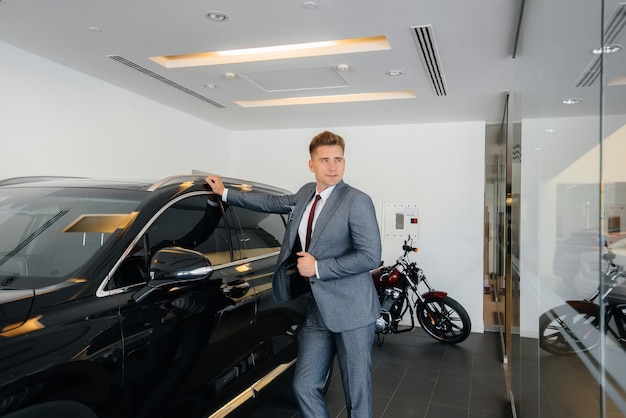 Een jonge zakenman kijkt naar een nieuwe auto in een autodealer