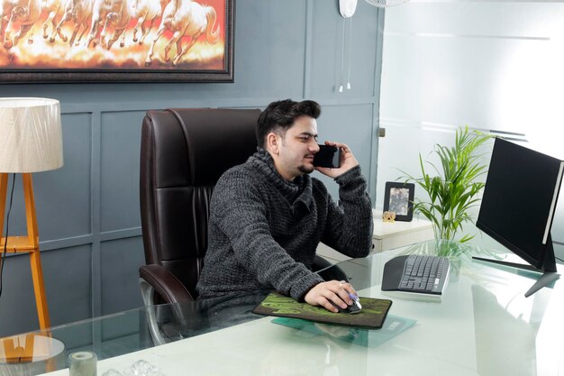 Een jonge zakenman zit op kantoor en praat op mobiele telefoon.
