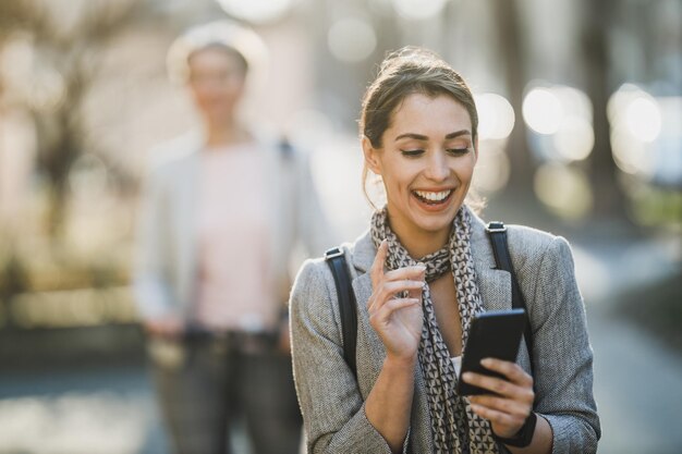 Een jonge zakenvrouw die smartphone gebruikt terwijl ze naar haar werk gaat.