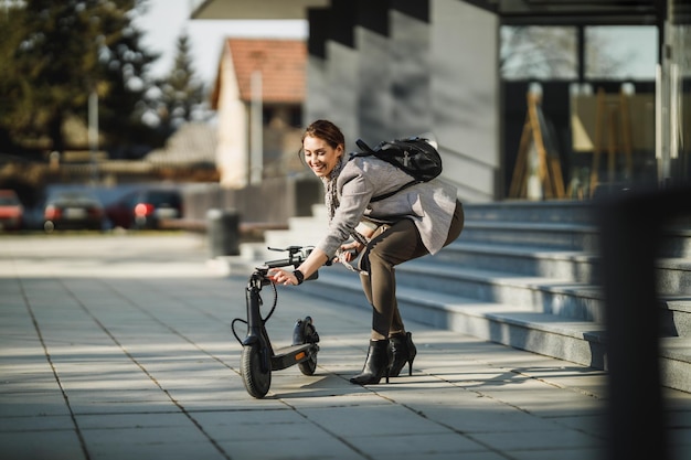 Een jonge zakenvrouw gaat aan de slag met een elektrische duwscooter.