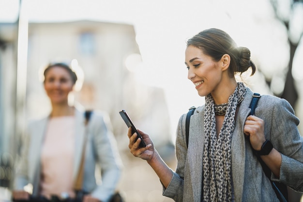 Een jonge zakenvrouw leest een bericht op een smartphone terwijl ze naar haar werk gaat.