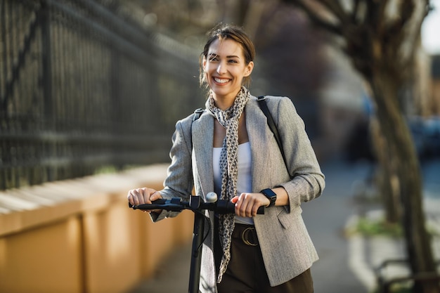 Een jonge zakenvrouw met een elektrische duwscooter die door de stad gaat werken.