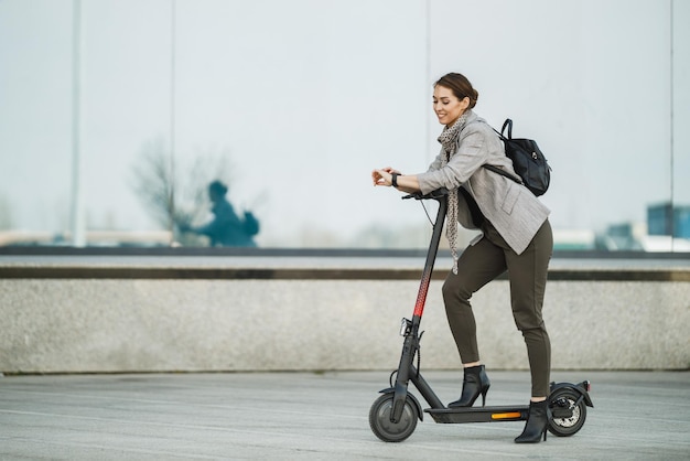 Een jonge zakenvrouw met een elektrische duwscooter gaat aan het werk.