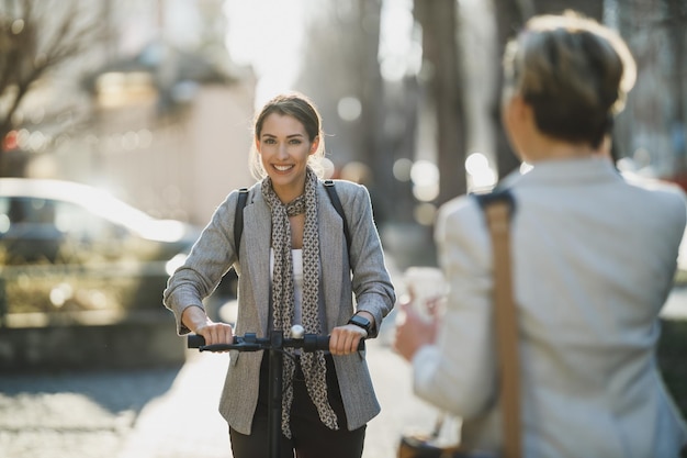 Een jonge zakenvrouw rijdt op een elektrische scooter op weg naar haar werk.