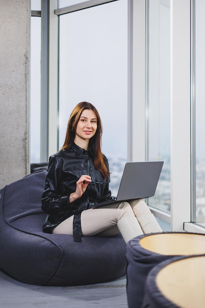Een jonge zakenvrouw zit terwijl ze aan een laptop werkt Het concept van een moderne succesvolle vrouw